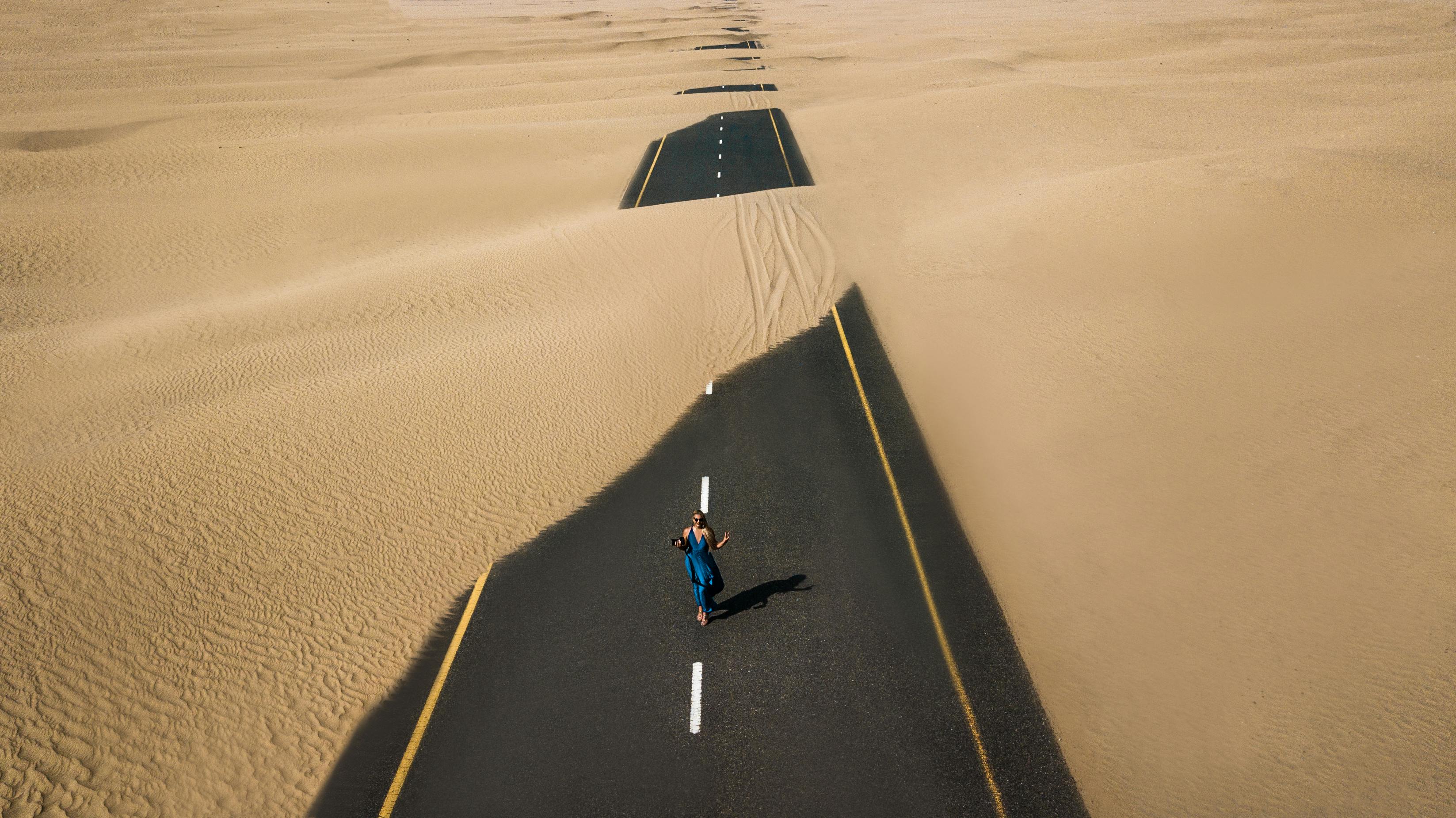 Picture of a man walking down a road, covered in sand"